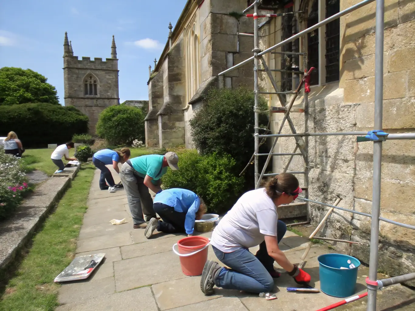 A vibrant image of volunteers restoring an ancient stone monument in a scenic rural setting, showcasing community involvement in heritage work.